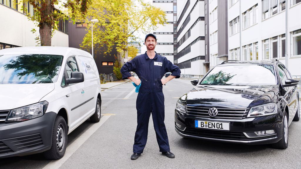 Automechaniker steht vor einem weißen und einem schwarzen Auto